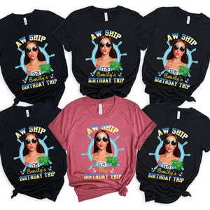 May include: A collection of black and maroon t-shirts featuring a graphic of a woman wearing sunglasses inside a ship's wheel. The text on the shirts reads "AW SHIP" and "It's Emily's Birthday Trip."