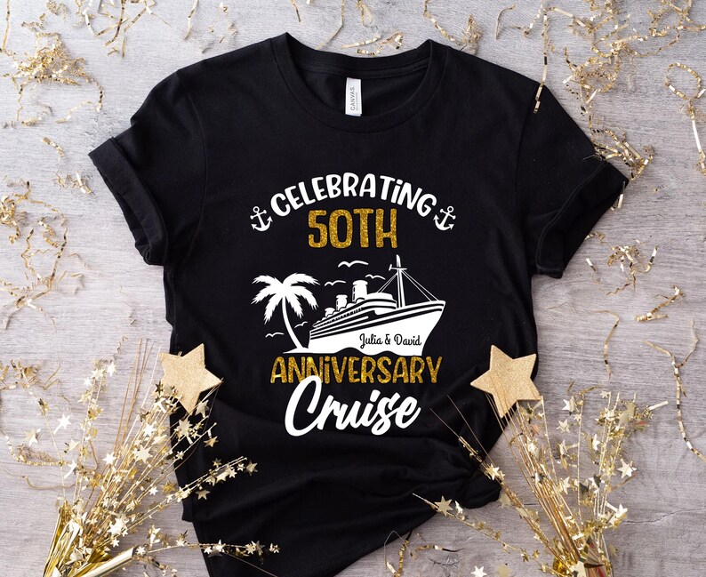 May include: Black t-shirt with a gold and white design celebrating a 50th anniversary cruise. The design includes a cruise ship, palm tree, and the names "Julia & David". The words "Celebrating 50th Anniversary Cruise" are also printed on the shirt.
