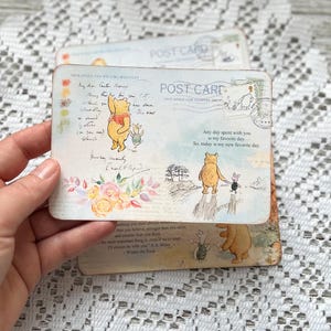 May include: Two Winnie the Pooh postcards featuring illustrations of Winnie the Pooh and Piglet. The text on the postcards reads "Any day spent with you is my favourite day. So, today is my new favourite day." and "Something you must always remember...than you believe, stronger than you seem, and smarter than you think...the most important thing is, even if we're apart, I'll always be with you." - A.A. Milne Winnie the Pooh