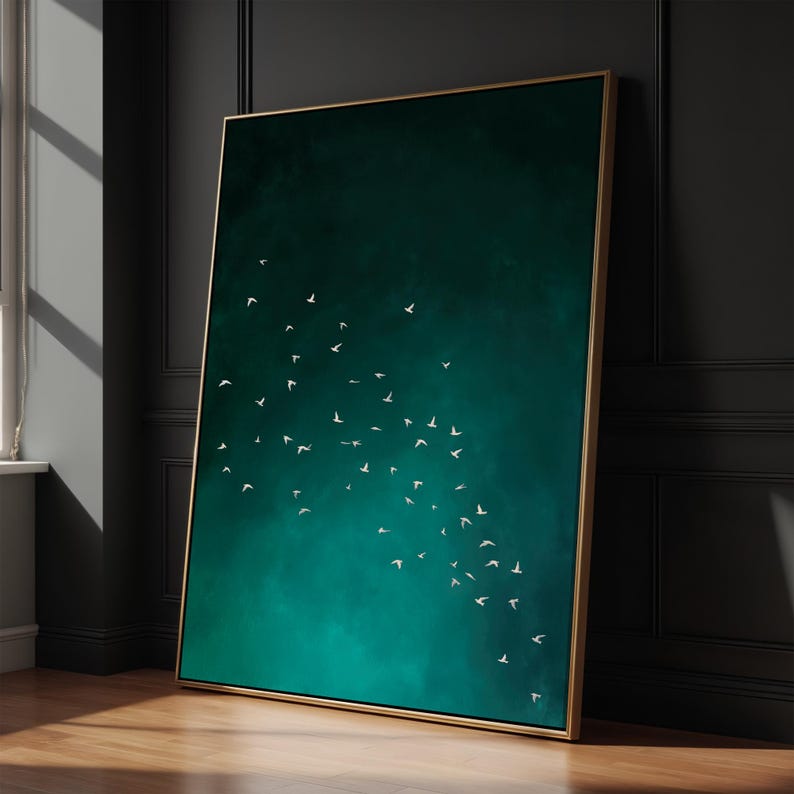 May include: A framed art print featuring a teal and emerald green background with a flock of white birds in flight. The artwork is displayed in a room with a wooden floor and a dark wall, and the frame is gold.