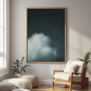 May include: A framed abstract painting depicting a single white cloud against a dark blue background. The painting is hanging on a white wall in a room with a wooden chair and a potted plant.