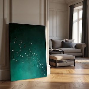 May include: A large canvas art print featuring a dark teal and green gradient background with a flock of white birds in flight. The artwork is leaning against a white wall in a well-lit room with a sofa and ottoman.
