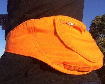May include: A bright orange safety belt with a zippered pocket. The belt is made of a thick, durable fabric and is designed to be worn around the waist.