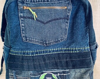 May include: A denim backpack with multiple shades of blue. The front pocket has a zipper with a green pull. A patch on the front reads "Save the Earth." The backpack is made from recycled denim.
