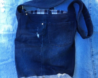 May include: A dark blue denim tote bag with a large pocket on the front. The bag has a long strap and is made from recycled denim.