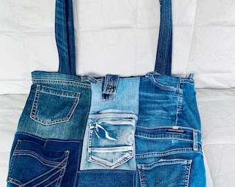 May include: A blue denim tote bag made from repurposed jeans. The bag has multiple pockets and is patchwork style.
