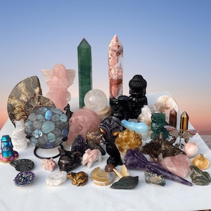 Pode incluir: Uma cole&ccedil;&atilde;o de v&aacute;rios cristais e figuras esculpidas. O sortimento inclui torres polidas, esferas e esculturas de animais, como uma coruja, um sapo e um urso. A paleta de cores apresenta pedras rosa, verdes, pretas e iridescentes, sobre um fundo gradiente suave.