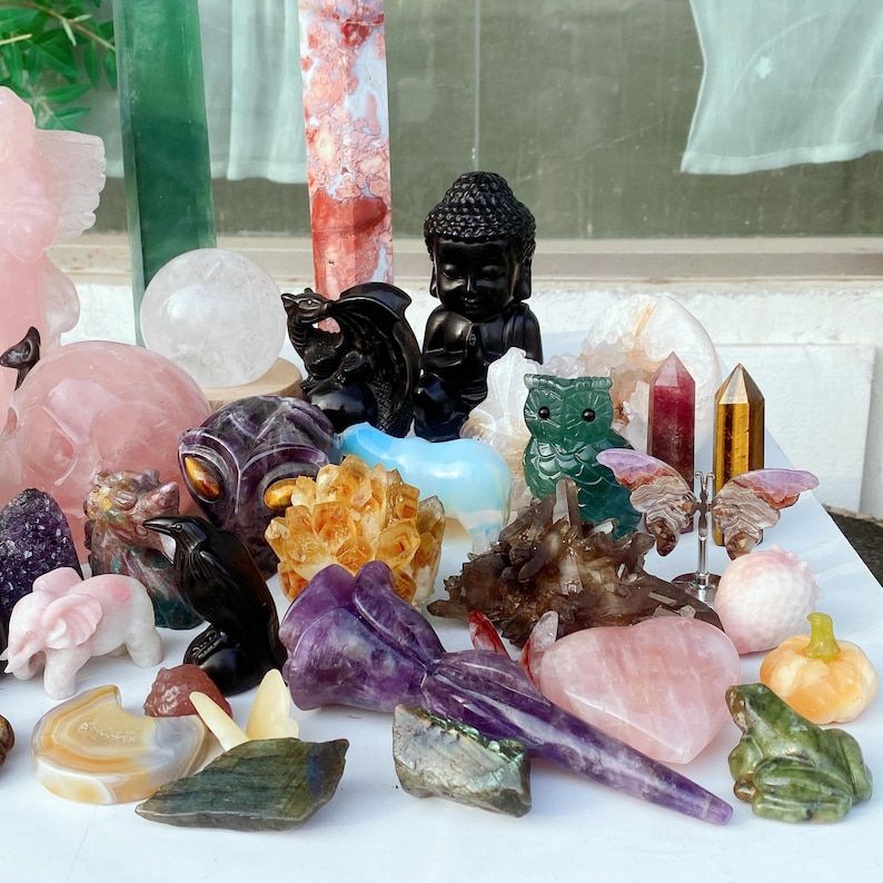 Pode incluir: Uma cole&ccedil;&atilde;o de v&aacute;rias esculturas de pedras preciosas e cristais. A variedade inclui uma est&aacute;tua de Buda preta, uma coruja verde, um drag&atilde;o preto, um cora&ccedil;&atilde;o rosa e uma ab&oacute;bora esculpida. Outros cristais incluem quartzo, ametista e citrino.