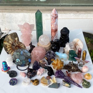 Pode incluir: Uma cole&ccedil;&atilde;o de v&aacute;rios cristais e figuras esculpidas. Inclui um anjo rosa, torres verdes e vermelhas, uma esfera transparente, um Buda preto e v&aacute;rias figuras de animais. Os cristais s&atilde;o de v&aacute;rias formas e cores.