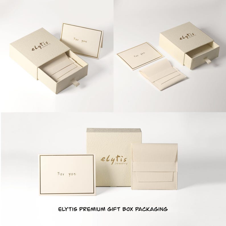May include: Cream-colored gift boxes and packaging with the "elytis" logo. The boxes are open, revealing a soft interior. Included are small cards with "For you" printed on them, and a small cream-colored pouch.