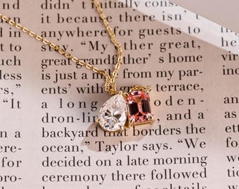 May include: A gold necklace with a pear-cut, clear gemstone and a rectangular, pink gemstone pendant. The chain is fine, creating an elegant piece of jewellery. The gemstones are set in a gold setting.