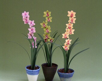 May include: Three potted orchid plants with pink, yellow, and orange flowers. The plants are in white, brown, and blue ceramic pots.