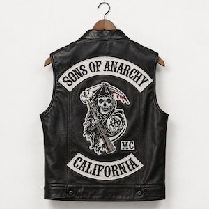 Puede incluir: Un chaleco de cuero negro con un gran parche bordado en la espalda. El parche muestra a una parca sosteniendo un rifle, con el texto Sons of Anarchy en la parte superior, California en la parte inferior y las letras MC en un recuadro.