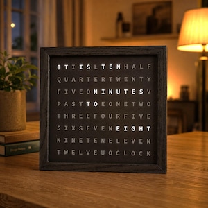 Pode incluir: Um relógio de palavras quadrado com uma moldura de madeira escura e um mostrador preto com letras brancas iluminadas. O texto brilhante mostra a hora IT IS TEN MINUTES TO EIGHT, com as palavras IT, IS, TEN, MINUTES, TO e EIGHT acesas.