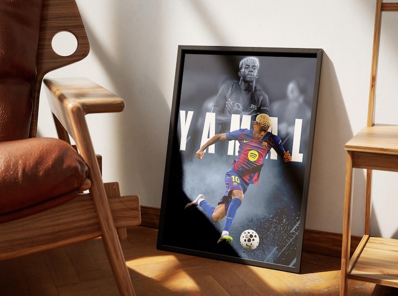 K&ouml;nnte beinhalten: Ein gerahmtes Poster mit einem Fu&szlig;ballspieler in einem blau-roten Trikot, der einen Ball tritt. Auf dem Poster steht der Name "YAMAL" in gro&szlig;en wei&szlig;en Buchstaben. Das Bild ist in einem schwarzen Rahmen, mit einem verschwommenen Bild des Spielers im Hintergrund.