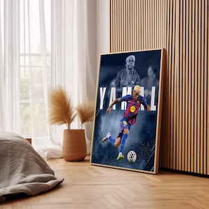 K&ouml;nnte beinhalten: Ein gerahmtes Poster mit einem Fu&szlig;ballspieler in einem blau-roten Trikot, der einen Fu&szlig;ball tritt. Auf dem Poster steht der Name "YAMAL" in gro&szlig;en wei&szlig;en Buchstaben. Der Hintergrund ist dunkelblau mit einem verschwommenen Bild des Spielers.