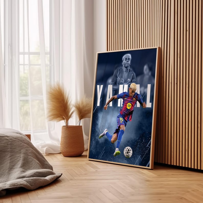 K&ouml;nnte beinhalten: Ein gerahmtes Poster mit einem Fu&szlig;ballspieler in einem blau-roten Trikot, der einen Fu&szlig;ball tritt. Auf dem Poster steht der Name "YAMAL" in gro&szlig;en wei&szlig;en Buchstaben. Der Hintergrund ist dunkelblau mit einem verschwommenen Bild des Spielers.