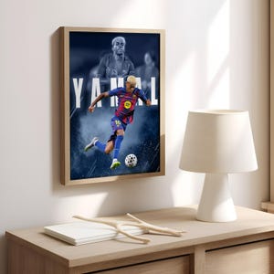 K&ouml;nnte beinhalten: Gerahmtes Poster mit einem Fu&szlig;ballspieler in blau-roter Uniform, der einen Fu&szlig;ball tritt. Der Name des Spielers, YAMAL, ist in gro&szlig;en wei&szlig;en Buchstaben dargestellt. Der Hintergrund hat einen blau-wei&szlig;en Raucheffekt.