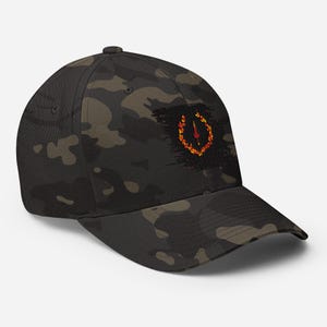 Puede incluir: Una gorra de béisbol de camuflaje negro y verde con un logotipo bordado en negro y naranja. El logotipo es una letra U estilizada con un diseño de llama.
