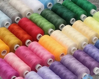 Puede incluir: Una colección de coloridas bobinas de hilo en varios tonos, incluyendo azul, verde, amarillo, rosa y morado. Las bobinas están cuidadosamente dispuestas, mostrando un espectro de colores para proyectos de costura y manualidades.
