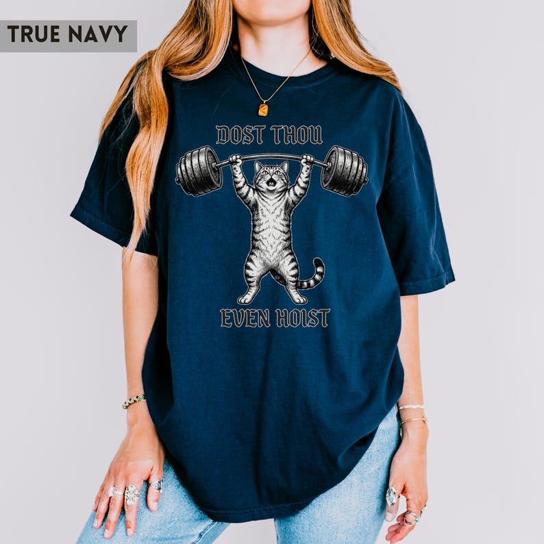May include: True navy blue t-shirt with a graphic of a cat lifting weights. The text reads "DOST THOU EVEN HOIST". The cat is grey and white, and the barbell is black. The shirt is a relaxed fit, suitable for casual wear.