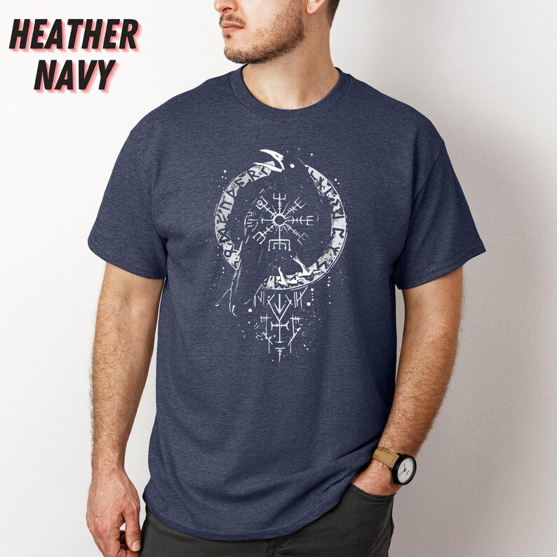 K&ouml;nnte beinhalten: Marineblaues meliertes T-Shirt mit wei&szlig;em Grafikdesign. Das Design zeigt ein kreisf&ouml;rmiges Emblem mit einem kompassartigen Symbol in der Mitte, einen Raben und Runentext. Die Worte "HEATHER NAVY" sind oben links aufgedruckt.
