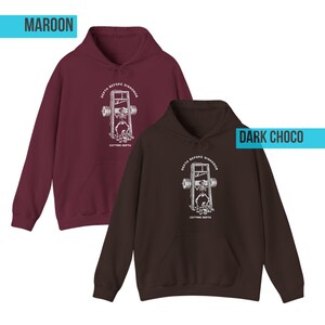 Puede incluir: Dos sudaderas con capucha, una granate y otra marr&oacute;n oscuro, con un gr&aacute;fico blanco de un esqueleto levantando pesas en una guillotina. El texto en las sudaderas dice "DEPTH BEFORE DISHONOR" y "CUTTING DEPTH".