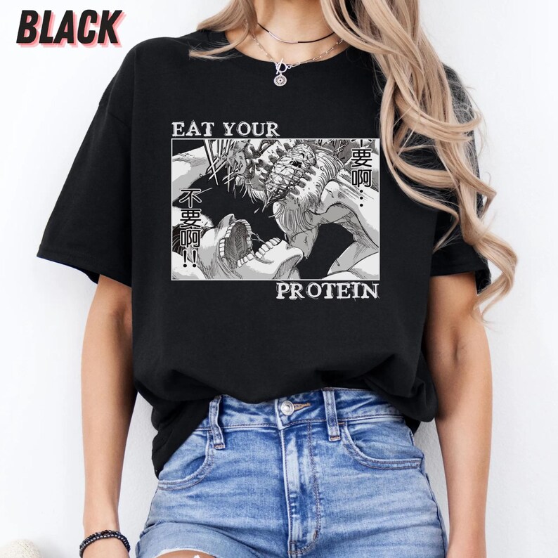 May include: Black t-shirt with a graphic design featuring a manga-style illustration and the text "EAT YOUR PROTEIN". The design includes Japanese text and a detailed black and white image.