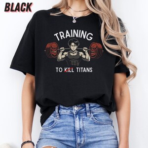 K&ouml;nnte beinhalten: Schwarzes T-Shirt mit dem wei&szlig;en Text "TRAINING TO KILL TITANS". Die Grafik zeigt eine muskul&ouml;se Figur, die eine Langhantel mit zwei rotgesichtigen Titanen an jedem Ende hebt. Das Wort "BLACK" steht oben links.