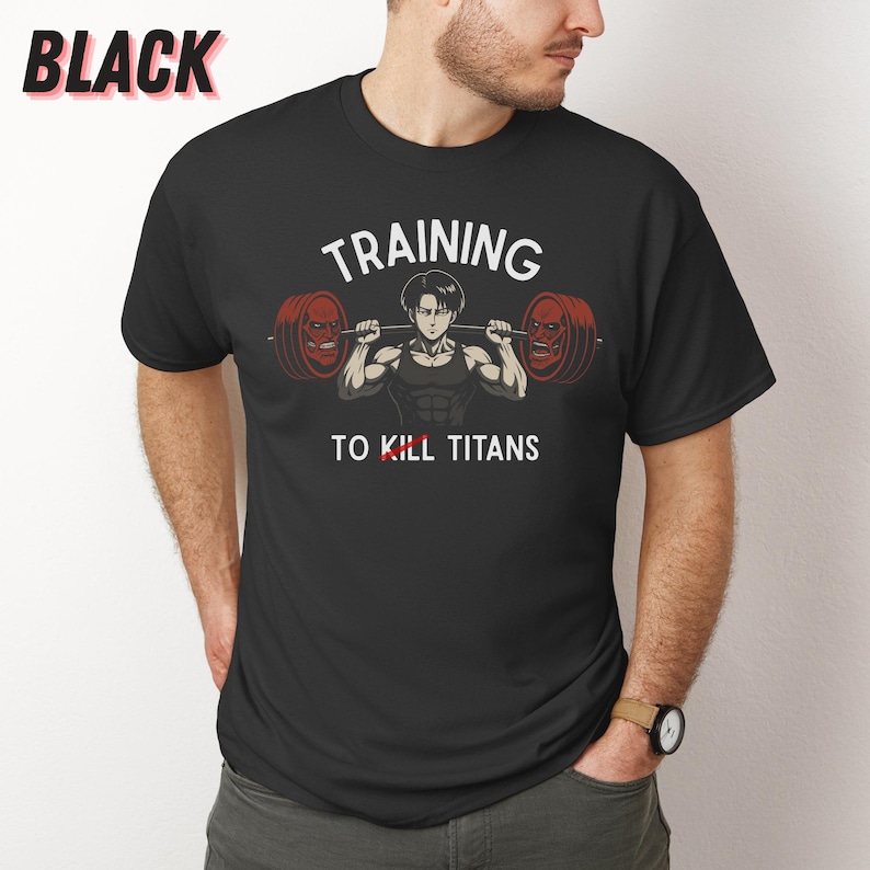 K&ouml;nnte beinhalten: Schwarzes T-Shirt mit einer Grafik eines muskul&ouml;sen Charakters, der Gewichte hebt, mit dem wei&szlig;en Text "TRAINING TO KILL TITANS". Das Wort "BLACK" befindet sich in der oberen linken Ecke.