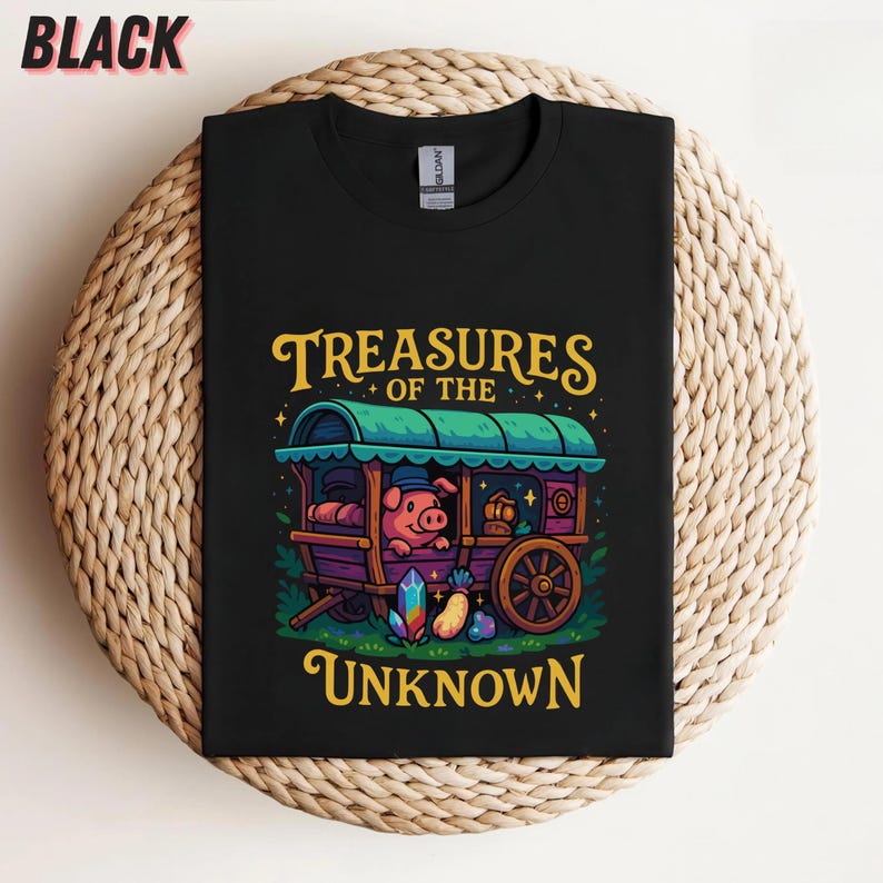 May include: Black t-shirt featuring a whimsical illustration of a pig in a caravan with the text "Treasures of the Unknown" in yellow. The caravan is purple and green, with a wooden wheel and colorful gems.