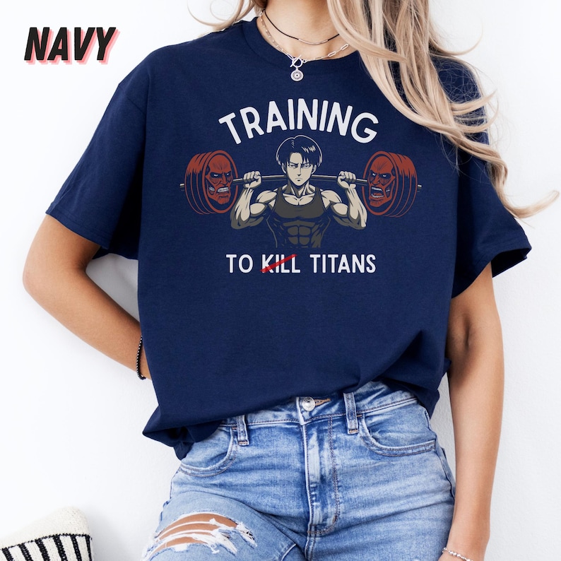 K&ouml;nnte beinhalten: Marineblaues T-Shirt mit dem Wort "NAVY" in der oberen linken Ecke. Das Shirt zeigt eine Grafik eines muskul&ouml;sen Anime-Charakters, der eine Langhantel hebt, mit den Worten "TRAINING TO KILL TITANS" in Wei&szlig;.