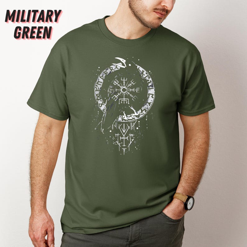 K&ouml;nnte beinhalten: Milit&auml;rgr&uuml;nes T-Shirt mit einem wei&szlig;en Grafikdesign eines Raben in einem kreisf&ouml;rmigen Rahmen mit Runen. Der Text "MILITARY GREEN" befindet sich oben links. Das Shirt besteht aus einem weichen, bequemen Material.