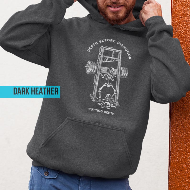 Puede incluir: Sudadera con capucha gris jaspeado oscuro con bolsillo delantero y capucha con cord&oacute;n. El gr&aacute;fico en la parte delantera presenta un esqueleto en una guillotina con las palabras "DEPTH BEFORE DISHONOR" y "CUTTING DEPTH" en blanco.