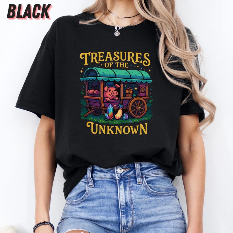 May include: Black t-shirt featuring a whimsical illustration of a pig in a caravan with the text "Treasures of the Unknown". The design includes a green roof, purple wagon, and colorful gems. The word "BLACK" is printed at the top.
