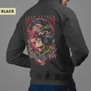 Puede incluir: Una sudadera con capucha negra que presenta un estampado gr&aacute;fico en la parte posterior. El dise&ntilde;o muestra una ilustraci&oacute;n estilizada de Eren Yeager con una transformaci&oacute;n monstruosa arriba, rodeada de acentos rojos y amarillos, con el texto EREN YEAGER.