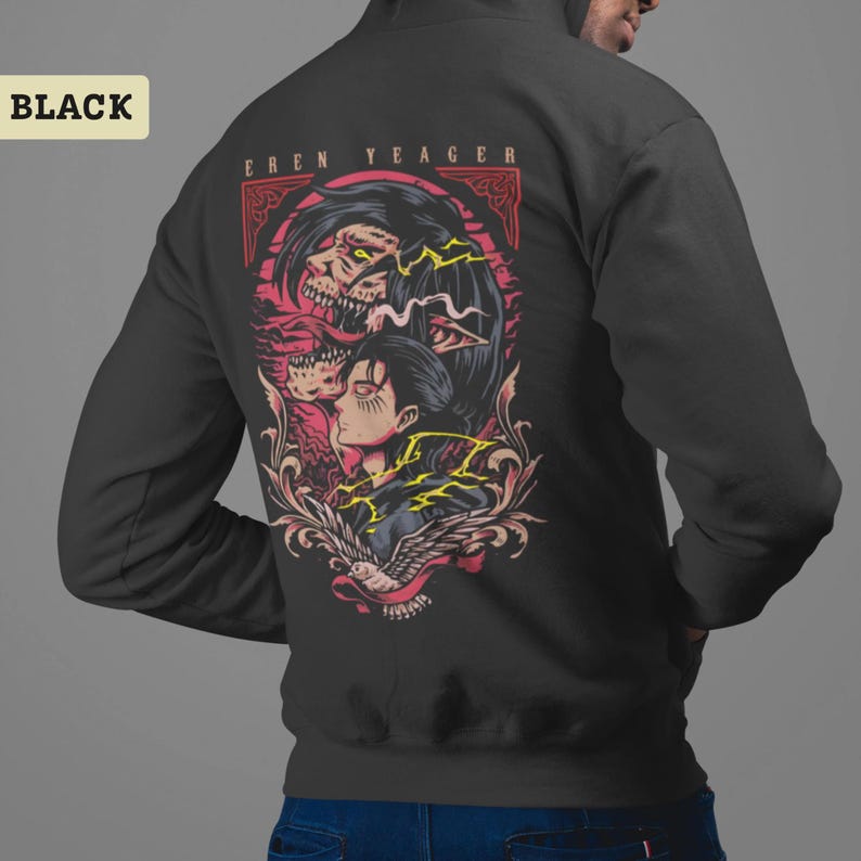 Puede incluir: Una sudadera con capucha negra que presenta un estampado gr&aacute;fico en la parte posterior. El dise&ntilde;o muestra una ilustraci&oacute;n estilizada de Eren Yeager con una transformaci&oacute;n monstruosa arriba, rodeada de acentos rojos y amarillos, con el texto EREN YEAGER.