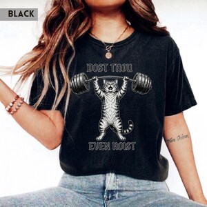 May include: Black t-shirt with a graphic of a cat lifting weights and the text "DOST THOU EVEN HOIST". The cat illustration is lifting a barbell. The shirt is a dark colour.
