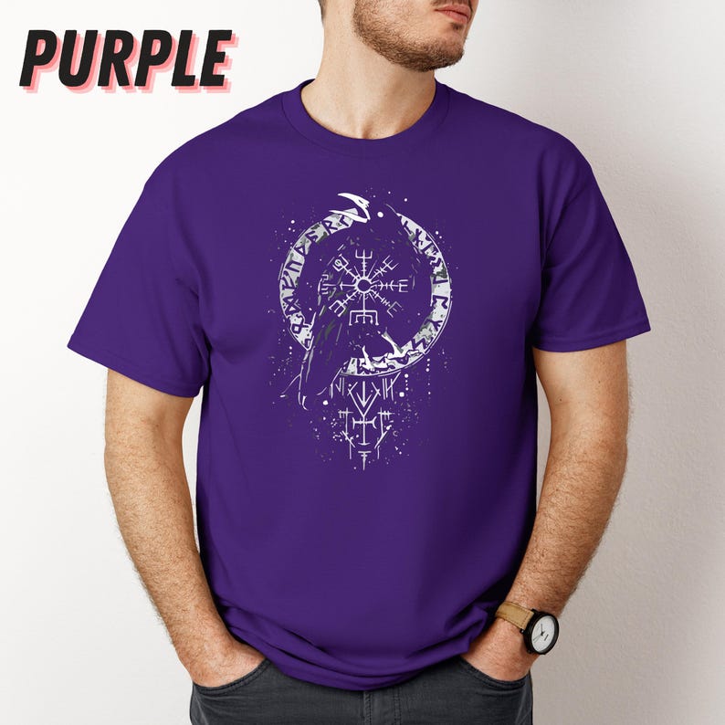 K&ouml;nnte beinhalten: Ein lila T-Shirt mit einer wei&szlig;en Grafik eines Raben und Runen in einem Kreis. Das Wort "PURPLE" ist oben links in Schwarz gedruckt. Das T-Shirt hat kurze &Auml;rmel und einen Rundhalsausschnitt. Eine Uhr wird getragen.