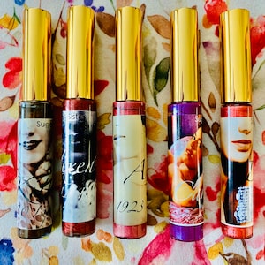 Puede incluir: Cinco peque&ntilde;os frascos de vidrio con tapas doradas y etiquetas. Las etiquetas presentan un retrato vintage de una mujer con el texto "Sugar", "Sister", "Angel 1923", "Carrie" y "Sugar".