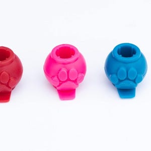 May include: Three round rubber dog chew toys in red, pink, and blue. Each toy has a paw print design.