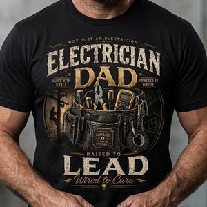 Könnte beinhalten: Schwarzes T-Shirt mit dem Text "ELECTRICIAN DAD" und einer Grafik von Werkzeugen in einem Werkzeuggürtel. Das Shirt enthält auch die Sätze "NOT JUST AN ELECTRICIAN", "BUILT WITH SKILL", "POWERED BY PRIDE", "RAISED TO LEAD" und "Wired to Care".