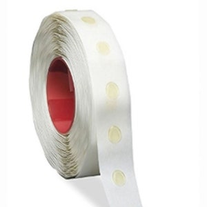 May include: A roll of white tape with clear adhesive dots. The tape is wound around a red core.