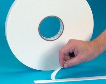 May include: A roll of white double-sided adhesive tape. The tape is being peeled off the roll by a hand.