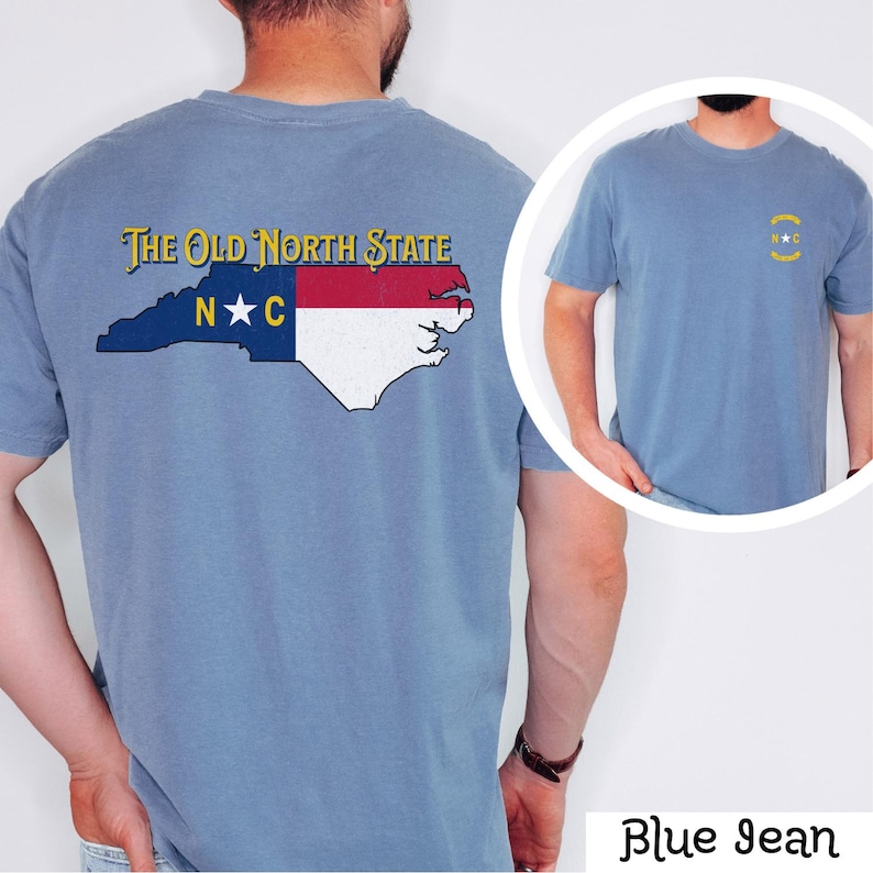 May include: A blue jean t-shirt with a vintage-style graphic of the North Carolina state flag and the text "The Old North State" on the back. The front of the shirt has a small graphic of the state flag with the letters "N.C." in a circle.