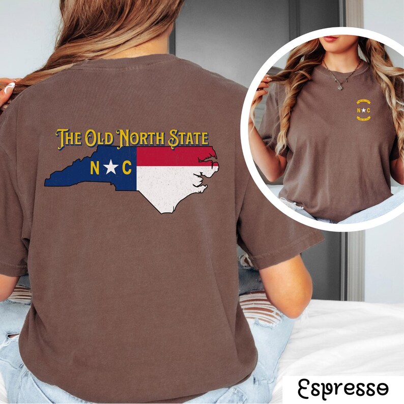 May include: Brown t-shirt with a graphic of the state of North Carolina and the text "The Old North State" on the back. The shirt is being worn by a person.