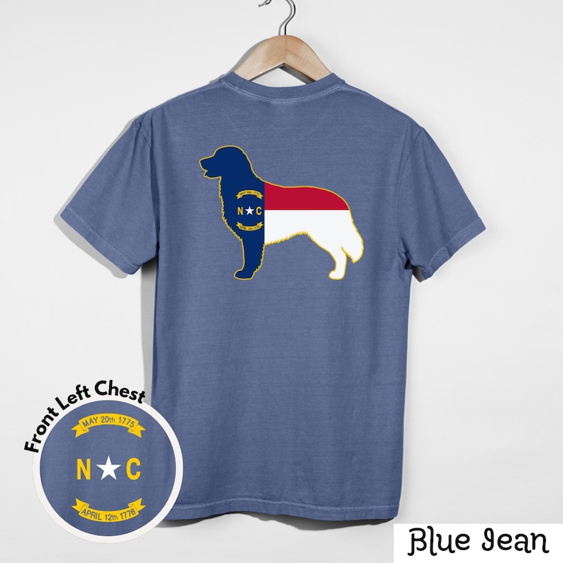 Puede incluir: Camiseta azul vaquero con un dise&ntilde;o de silueta de perro en la espalda, con la bandera del estado de Carolina del Norte. Un dise&ntilde;o circular m&aacute;s peque&ntilde;o en el pecho izquierdo delantero incluye el texto "N★C" y las fechas "MAY 20th 1775" y "APRIL 12th 1776".
