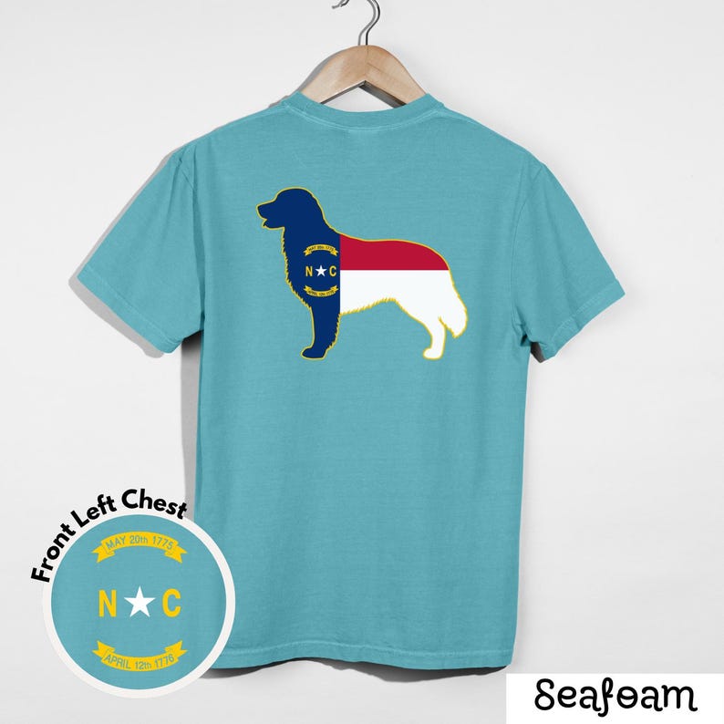Puede incluir: Camiseta verde mar con un dise&ntilde;o de silueta de perro en la espalda, con la bandera del estado de Carolina del Norte. El pecho izquierdo tiene un gr&aacute;fico circular con las letras "N" y "C" y las fechas "May 20th 1775" y "April 12th 1776".