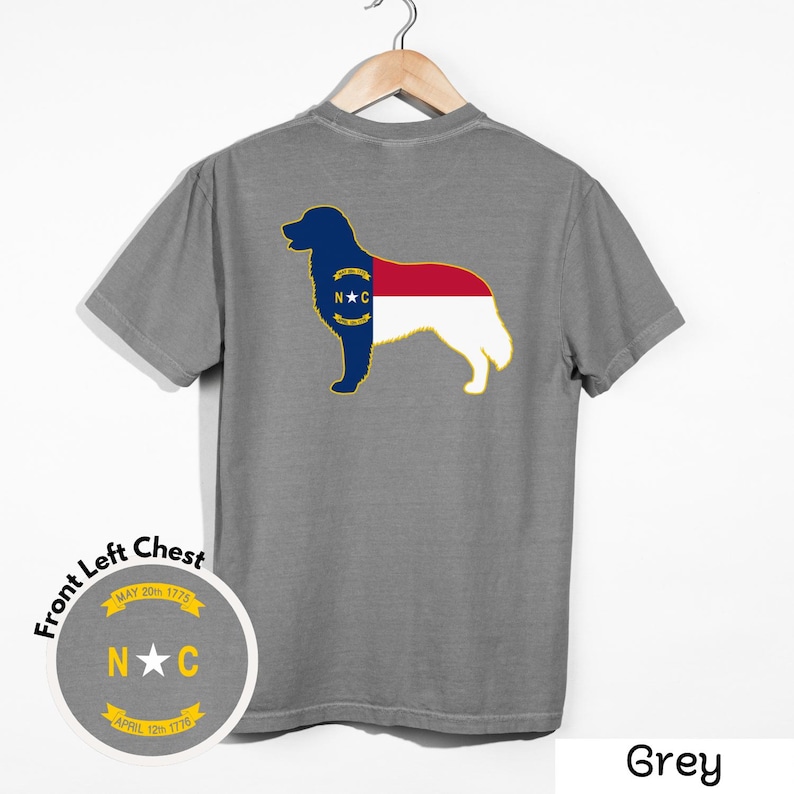 Puede incluir: Camiseta gris con la silueta de un perro y el dise&ntilde;o de la bandera del estado de Carolina del Norte en la espalda. El pecho izquierdo tiene un gr&aacute;fico circular con el texto "N C" y las fechas "20 de mayo de 1775" y "12 de abril de 1776".