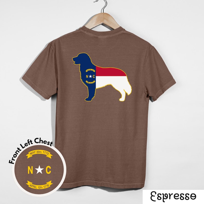 Puede incluir: Camiseta color espresso con una silueta de perro rellena con el dise&ntilde;o de la bandera del estado de Carolina del Norte. El frente izquierdo del pecho tiene un emblema circular con el texto: "Front Left Chest, MAY 20th 1775, N★C, APRIL 12th 1776."